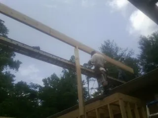 Carpenter setting a ridge beam over a new addition frame — Ice Dam Removal by Roofing Brothers in Middleville