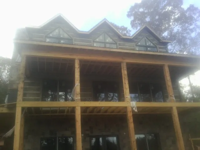Dormers and porch framing on a large log home under construction — Roof Coating work by our crew in Middleville