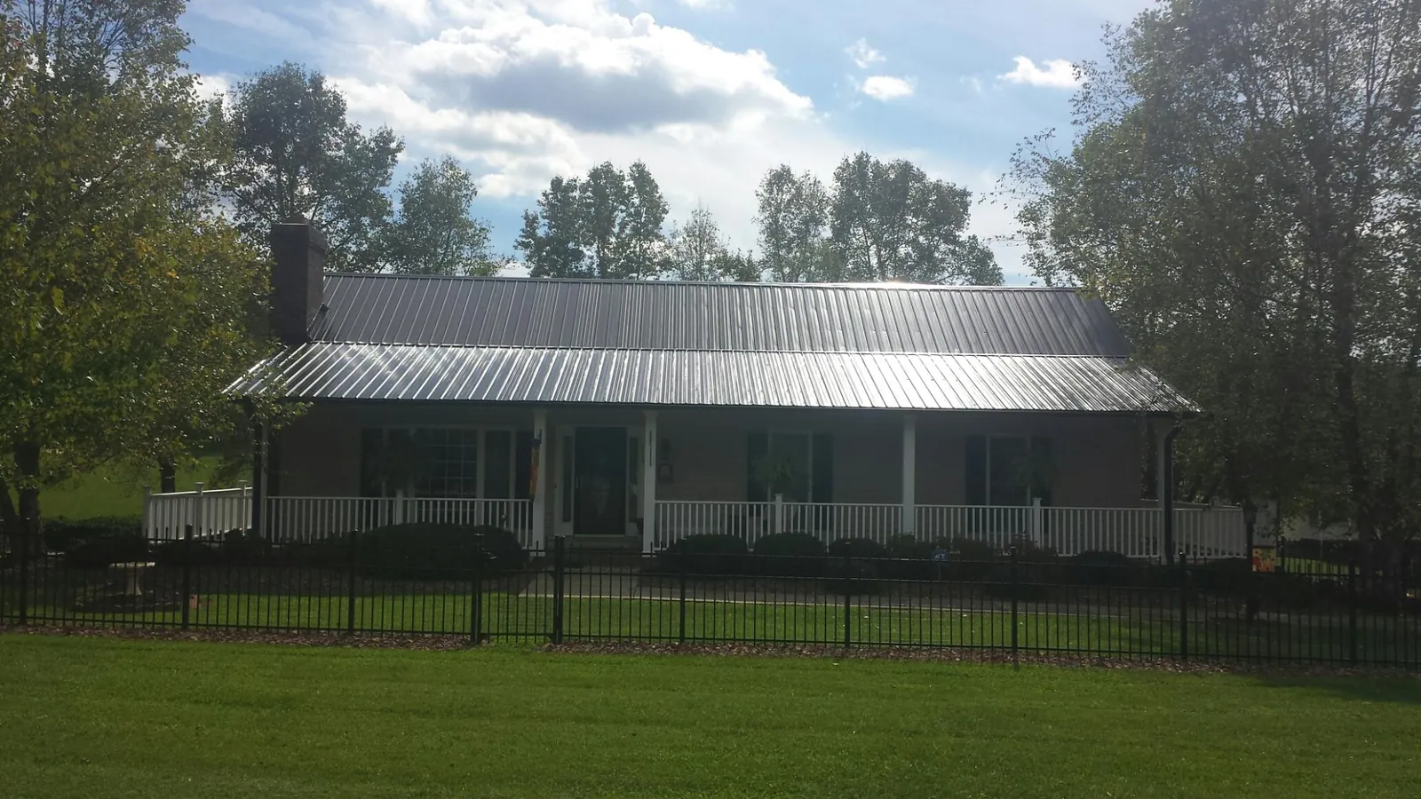 Gray metal roof on a brick ranch with a full width front porch — Gutter Guard Installation work by our crew in Middleville