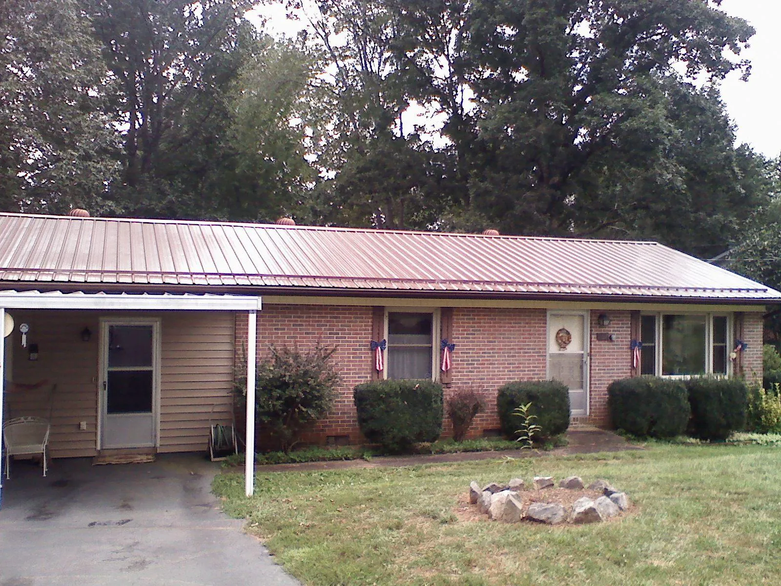 Bronze metal roof and carport on a brick ranch home — Roof Repair work by our crew in Middleville