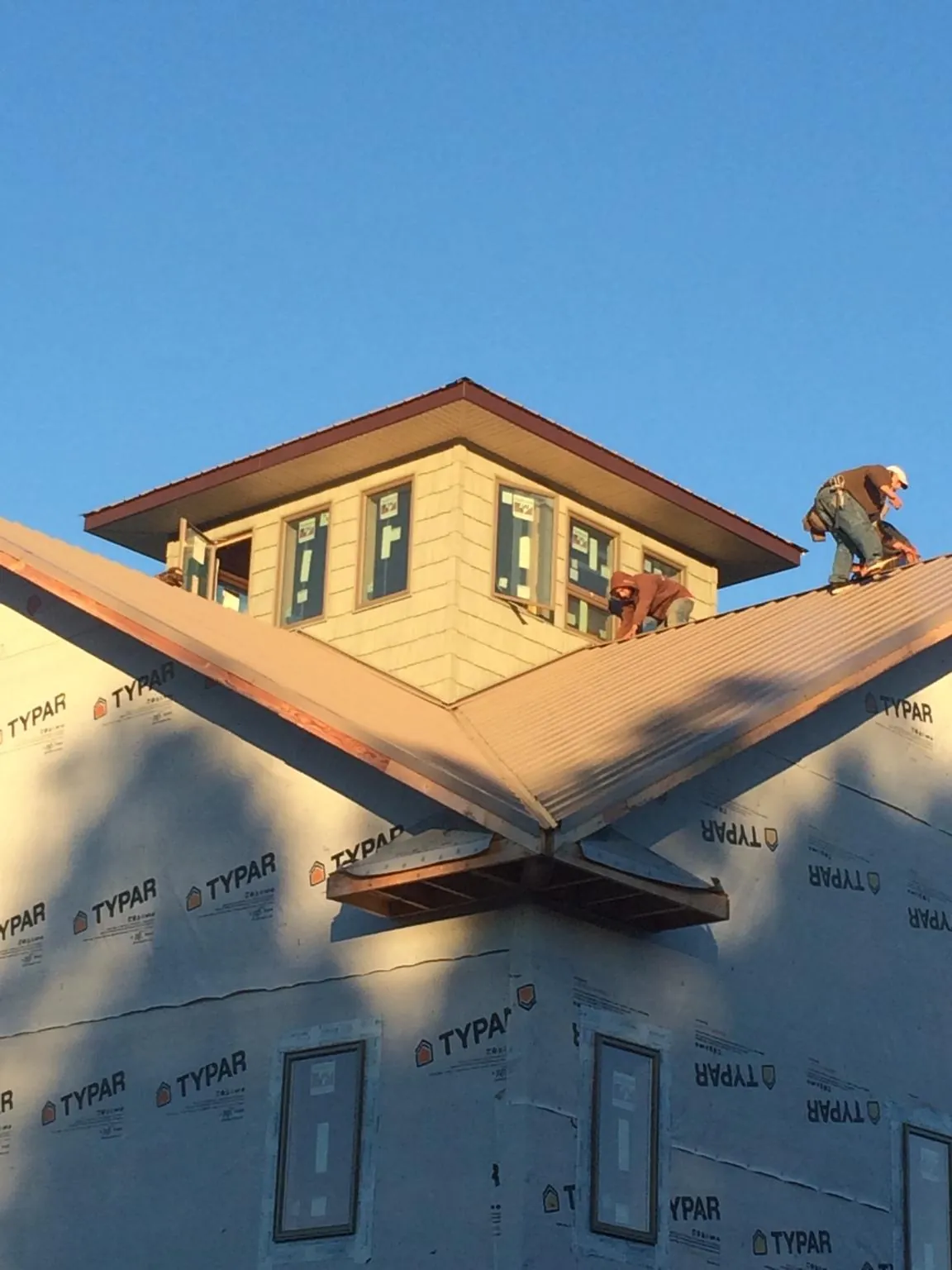 Roofers working around a rooftop cupola on a new metal roof at sunset — Roof Waterproofing in Middleville by Roofing Brothers